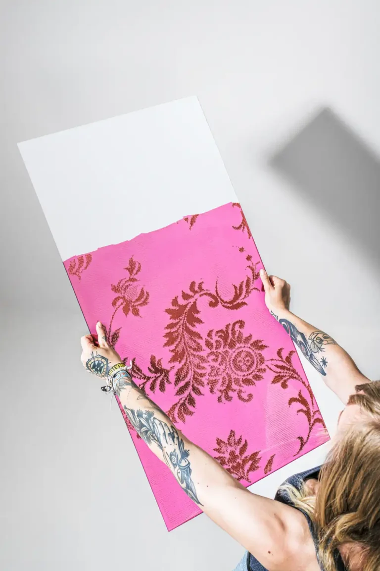 Kunstreproduktion – Tätowierte Hände halten rosa siebbedruckte Glasplatte mit Ornamentmuster von Quintstudio