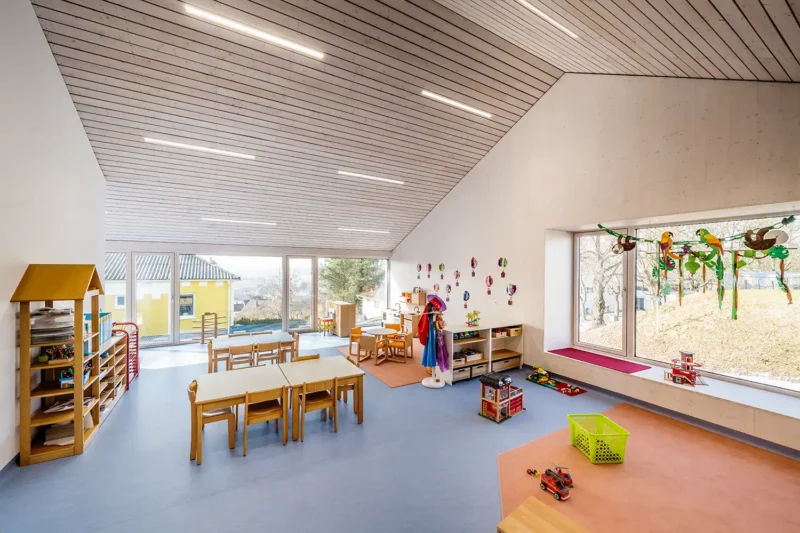 Architekturfotografie – Gruppenraum im Kindergarten Weitersfeld mit Holzdecke und großen Fenstern