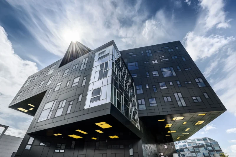 Architekturfotografie – WU Executive Academy Gebäude in Wien mit überhängenden Geschossen vor dramatischem Himmel