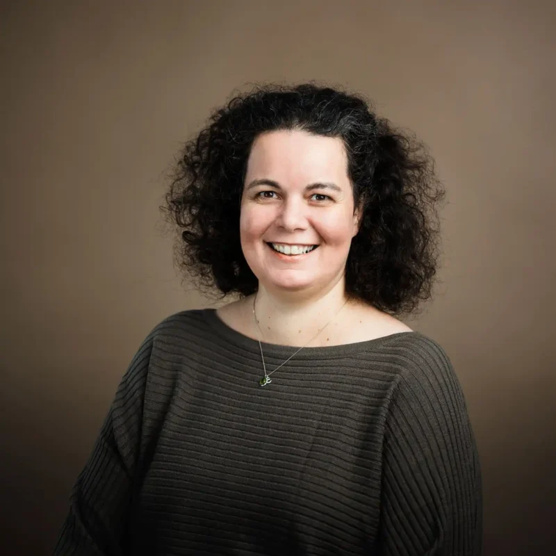 Businessportrait einer Frau mit schwarzem lockigem Haar und grauem Oberteil, BOKU Wien