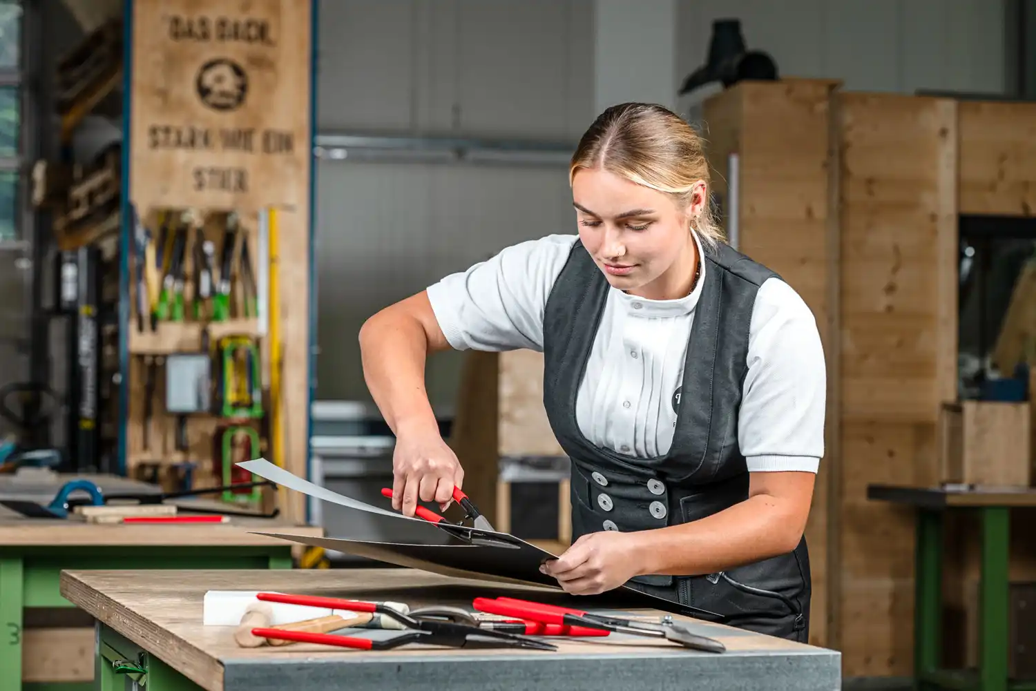 Editorial Portrait von Fabienne Ellermeier bei der Arbeit mit Metallblech in einer Werkstatt in Rheinbach