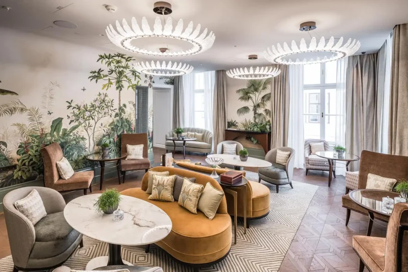 Interiorfotografie einer luxuriösen Hotellobby mit tropischer Wandtapete, Designer-Leuchten und Samtmöbeln in Ocker und Grau